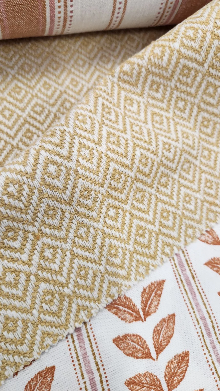 Ochre-and-cream small diamond/geometric weave beside striped and leaf-patterned samples.