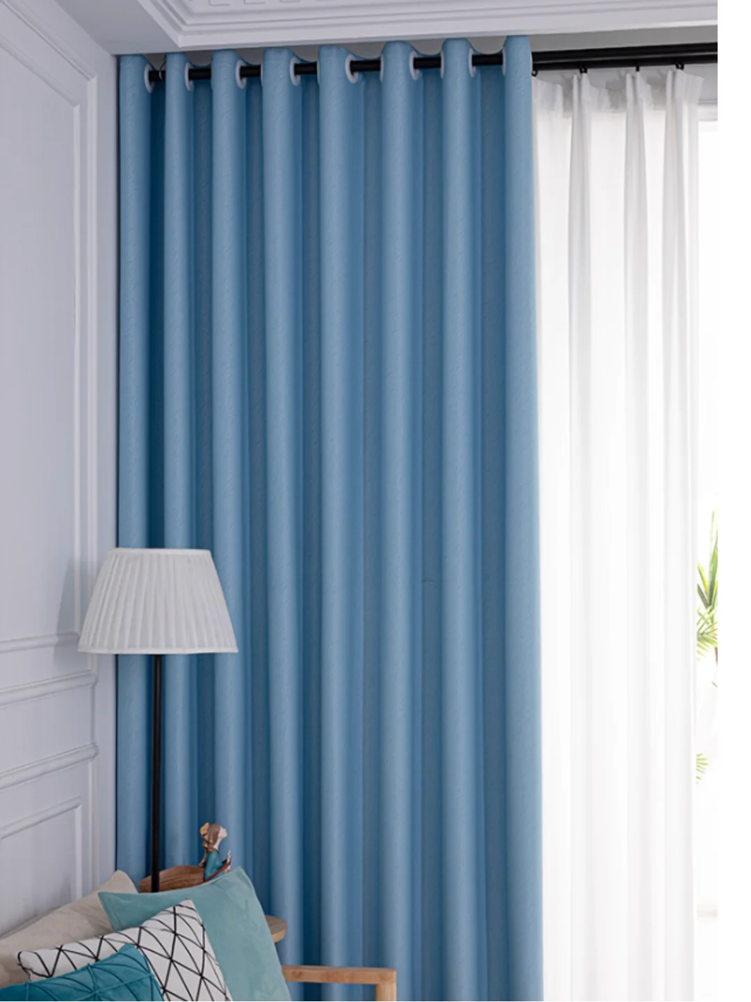Blue opaque curtain suspended on a dark pole through large visible metal grommet rings.
