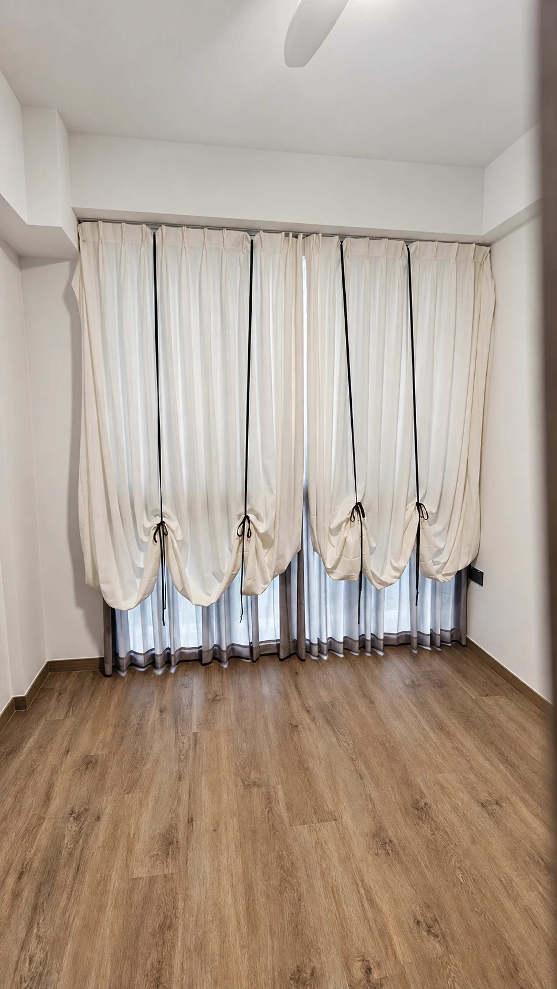 Ribbon gathering, ivory curves & grey sheer layer — close-up of the supplied curtain photograph.